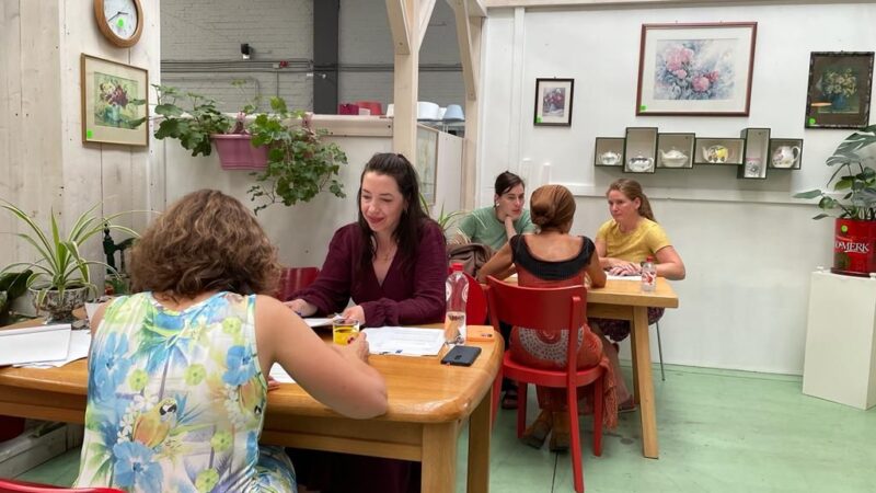 Aan 2 tafels wordt er getest. Aan de ene tafel zit Talissa met een testpersoon. Aan de andere tafel zitten Eline en Madelon met een andere testpersoon.