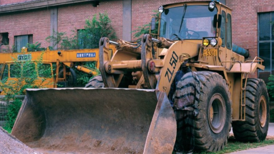 De graafmachine uit het voorbeeld in de tekst. De graafmachine is geel en heeft grote banden.
