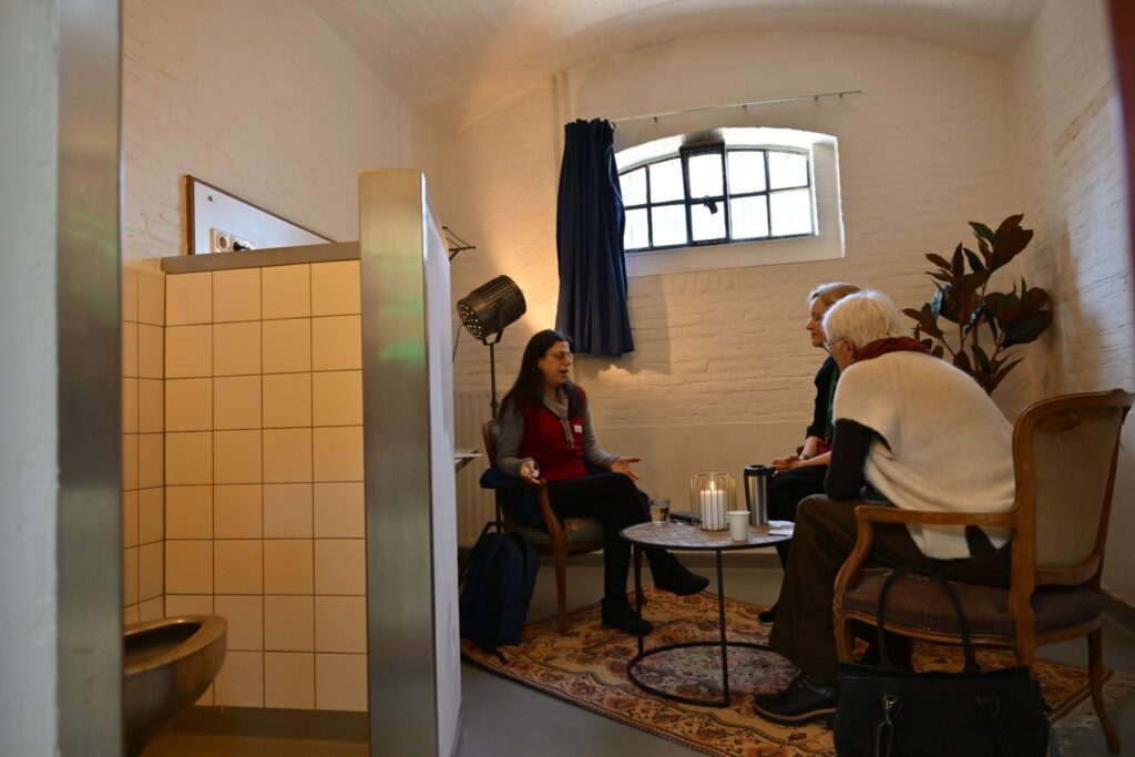 Mensen in gesprek in een cel van de voormalige Koepelgevangenis.