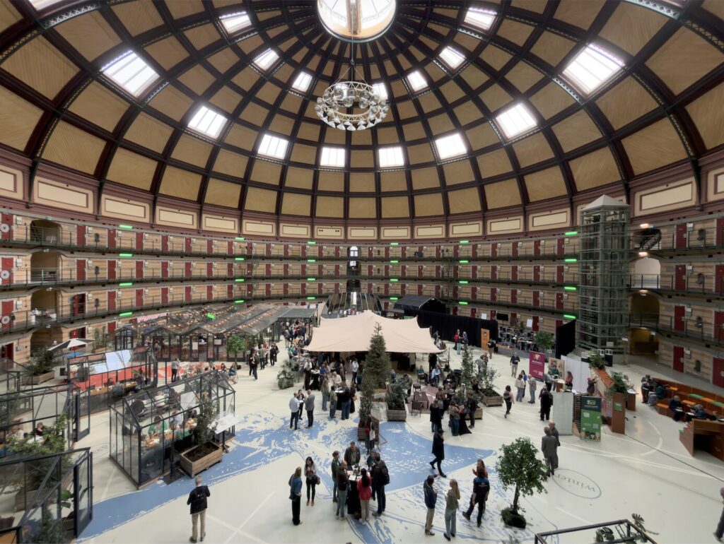 Binnenkant van de Koepelgevangenis: cellenblokken en een groot plein met deelnemers van de conferentie.