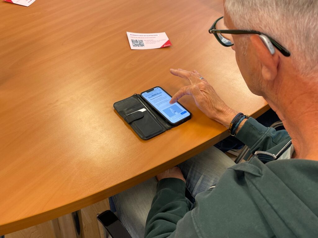 Een taalambassadeur van Team Ervaringsdeskundigen Rotterdam Rijnmond test een website op zijn telefoon.